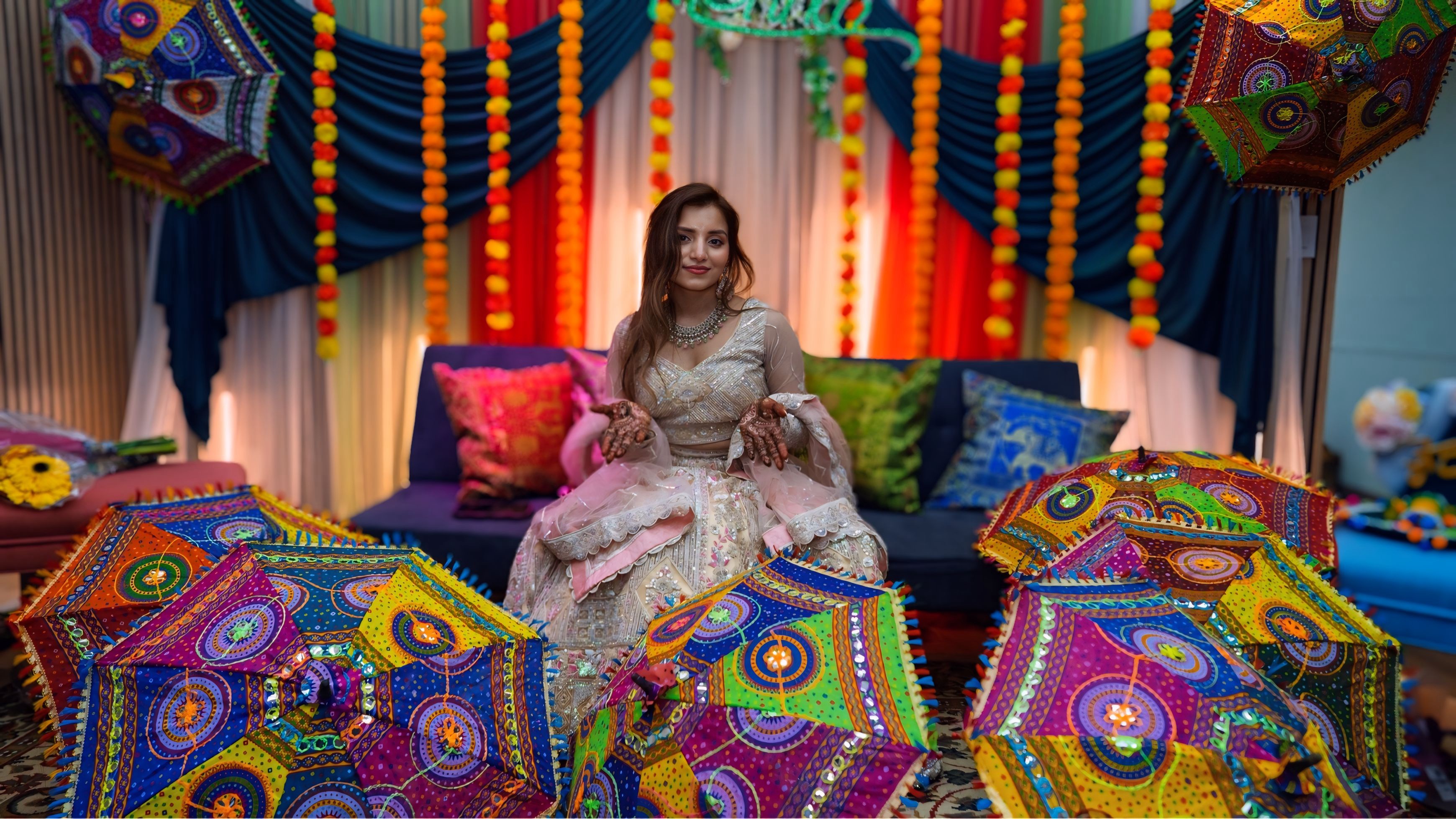 Bride surrounded by colorful Rajasthani umbrellas at vibrant mehndi ceremony